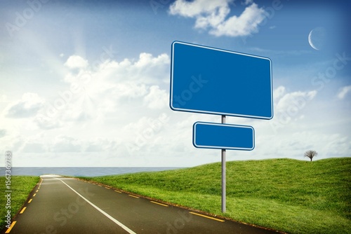 Flat design illustration is showing blank blue road sign on coastal road with leafless hilltop tree