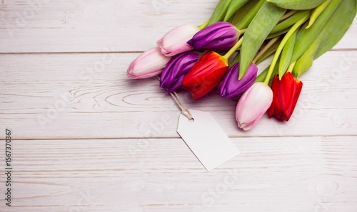 Fototapeta Naklejka Na Ścianę i Meble -  Multicolor tulip bouquet is lying on painted wooden plank in flat design with blank gift tag