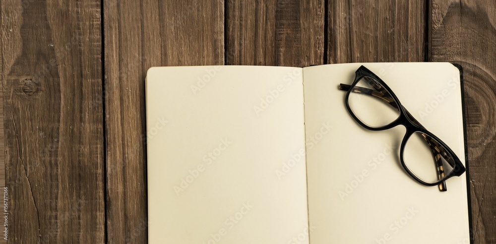 Fototapeta premium Overhead view of reading glasses on blank book