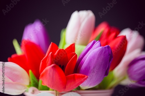 Flat design is showing multicolored tulip bouquet with light-colored container and green stems