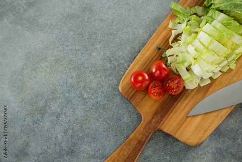 Chopped lettuce with tomato on cutting board