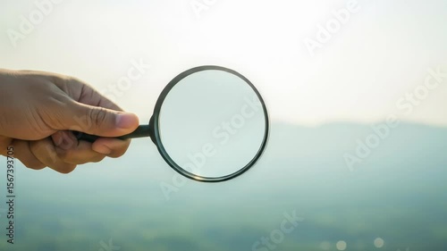Hand Holding Magnifying Glass Over Landscape, Searching, Exploring, Discovery.