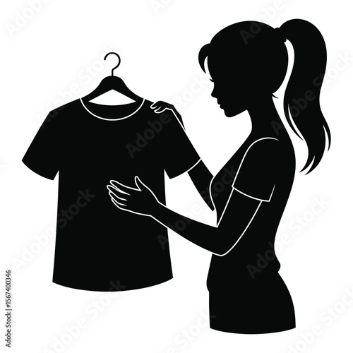 Silhouette of a woman choosing a black t shirt from a hanger