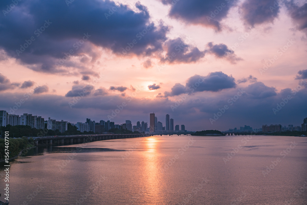 Fototapeta premium A view of the sunset city of Yeouido in the financial district taken on the Dongjak Bridge on the Han River in summer evening 