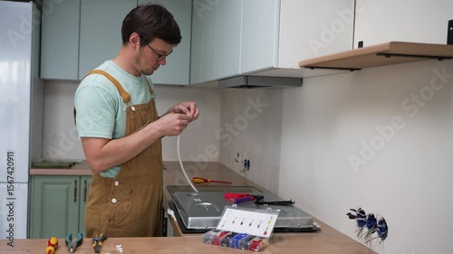 Professional electrician carefully connects wires to a new electric stove during kitchen renovation, ensuring proper installation and electrical safety