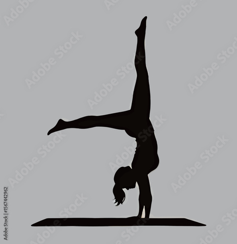 Silhouette of a woman performing a handstand yoga pose on a mat.