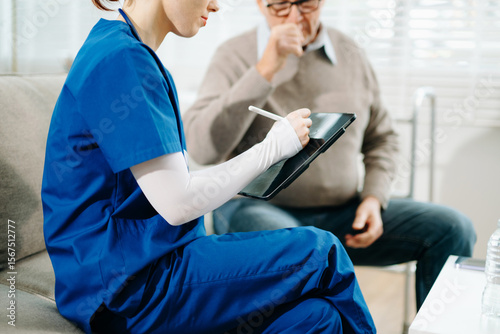 Senior man with chest pain speaks to nurse noting symptoms on tablet at home. Healthcare, heart health