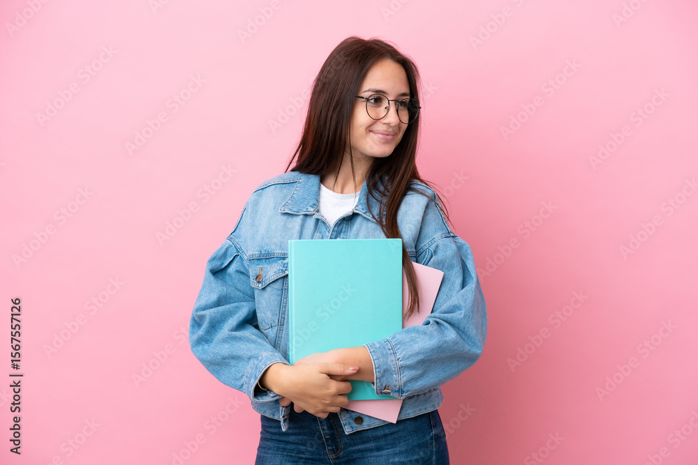Fototapeta premium Young Ukrainian student woman isolated on pink background looking to the side and smiling