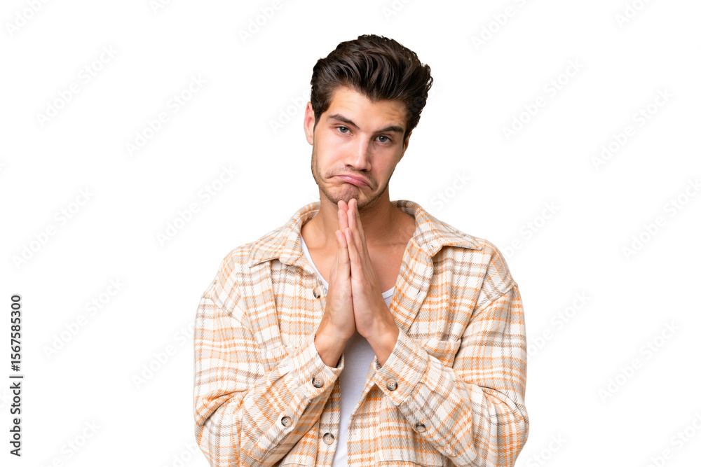 Young handsome caucasian man over isolated background keeps palm together. Person asks for something Young handsome caucasian man over isolated background keeps palm together. Person asks for something