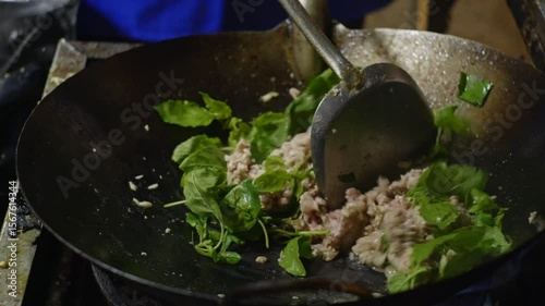 Close-up shots of stir-frying minced meat with red chili peppers in a hot wok over an open flame, with visible smoke and fire during cooking