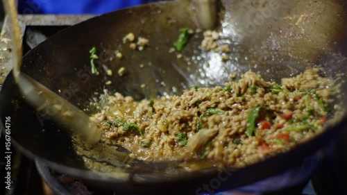 Close-up shots of stir-frying minced meat with red chili peppers in a hot wok over an open flame, with visible smoke and fire during cooking