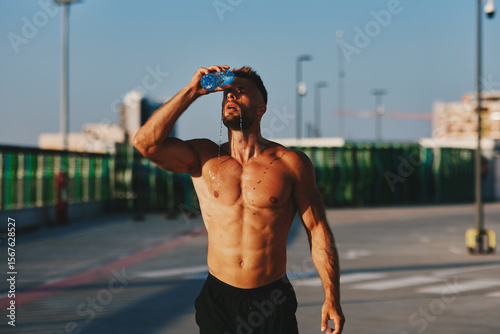 Tableau sur toile Sweaty sportsman pouring water on himself after training outdoors
