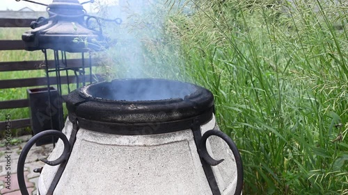 Burning firewood with smoke in traditional tandoor oven, top view. Rustic cooking and heating concept.

