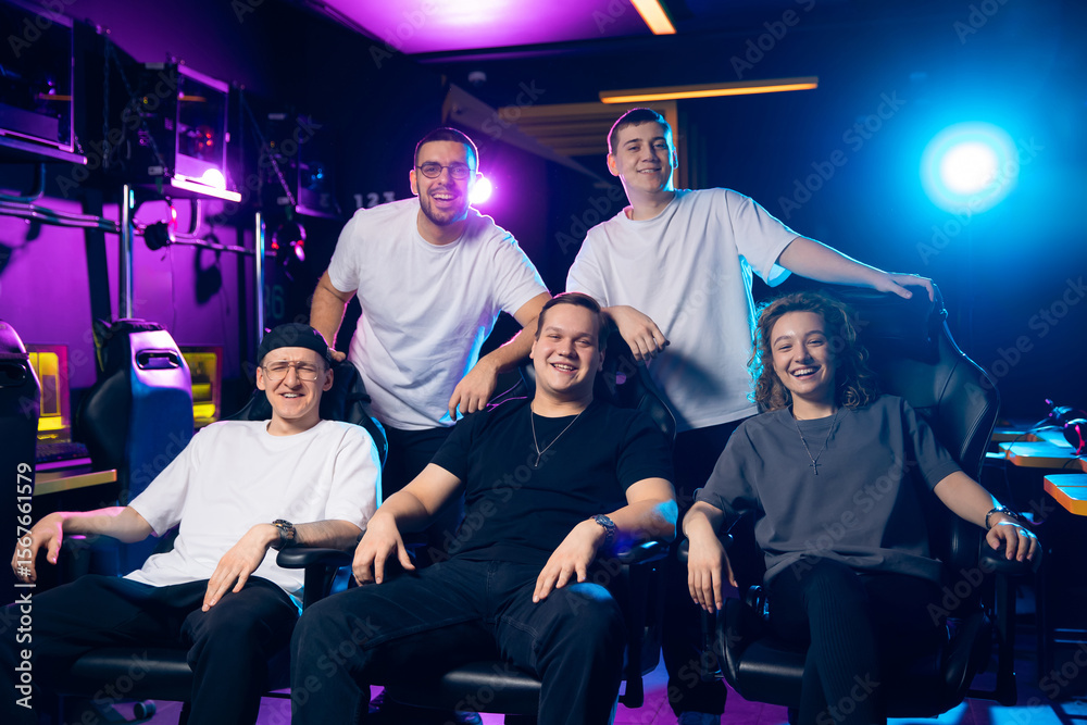 Obraz premium Portrait happy team of esports. Diverse group of young adults enjoying gaming in neon-lit room