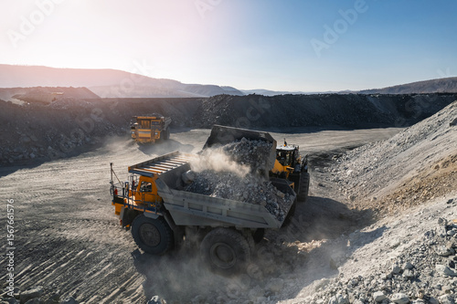 Heavy industrial wheel loader at mining site, temporary storage of ore for loading to big truck and transportation to mine and processing plant, aerial view