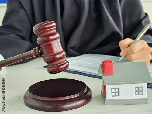 Court judge reviewing real estate matter with gavel and house on desk during legal proceedings