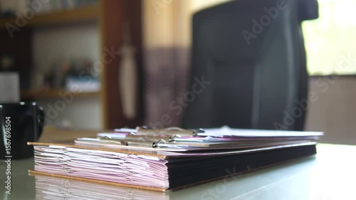 Stack of documents and clipboard on office desk in morning light