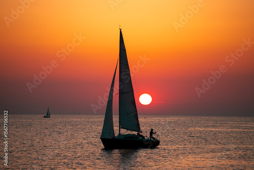 Sailing boat silhoutted against the orange sky
