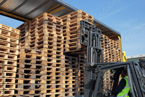 Counterbalance driver unloading empty euro pallets for local warehouse.