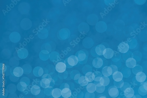 Out of focus luminous spots against a blue backdrop with bokeh effect