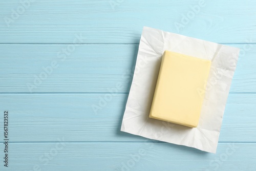 Delicious butter block on a pastel blue wooden surface, top-down perspective with space for customization
