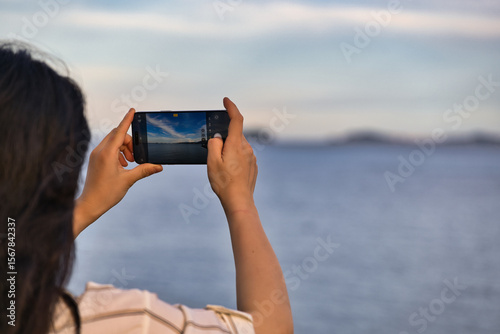 A Woman Taking a Photo of the Sea with Her Smartphone