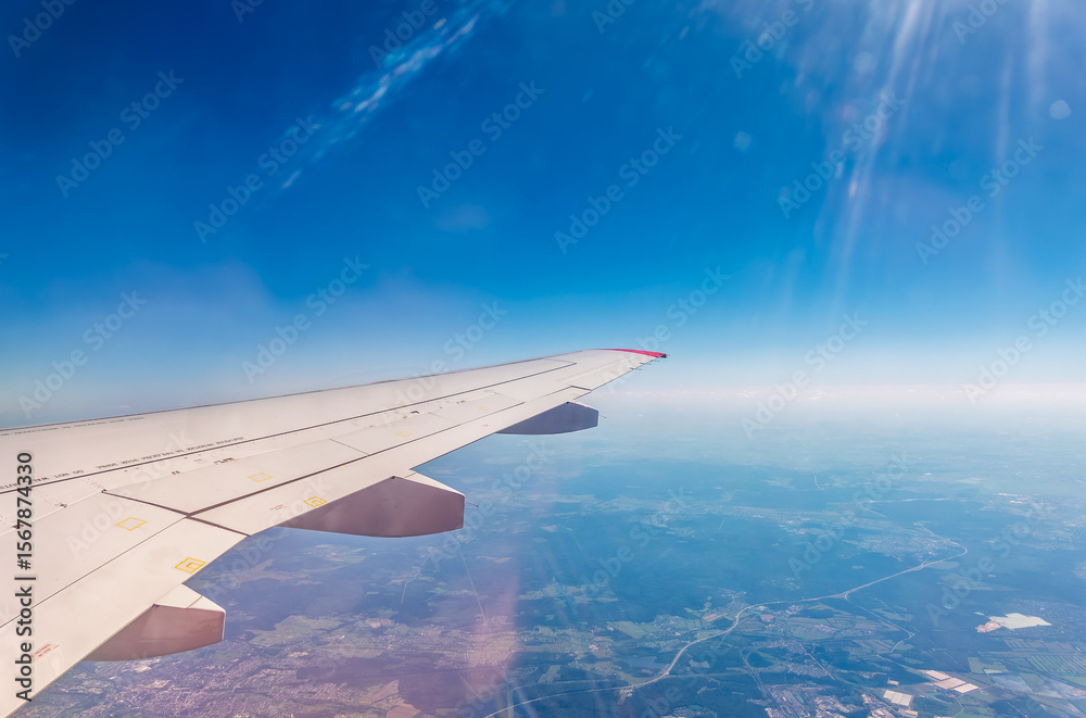 Fototapeta premium View from the airplane window at a beautiful cloudy sky and the airplane wing