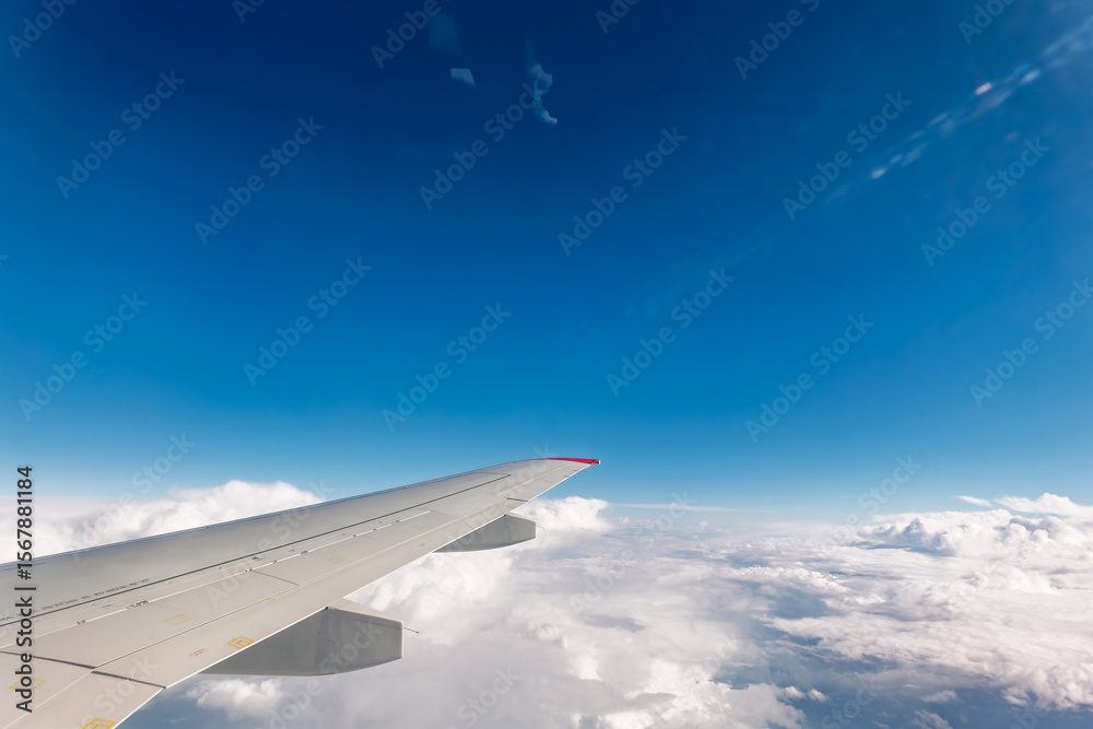 Fototapeta premium View from the airplane window at a beautiful cloudy sky and the airplane wing