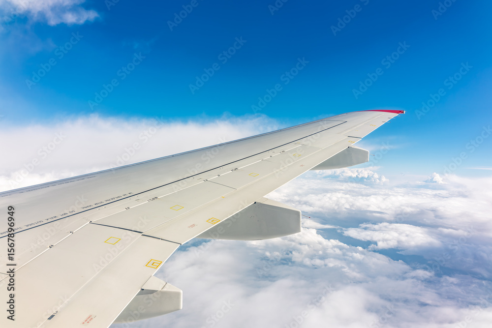 Fototapeta premium View from the airplane window at a beautiful cloudy sky and the airplane wing