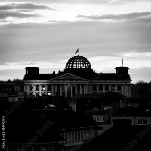 Monochrome view of the reichstag building in berlin under a cloudy sky at dusk with rooftops in foreground
