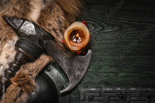 Billede på lærred Medieval Viking axe and warrior wooden green black shied on old warrior table close up background