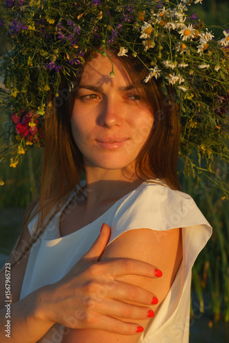 Portrait of a girl in a white dress, Slavic appearance with a wreath of wild flowers on her head.