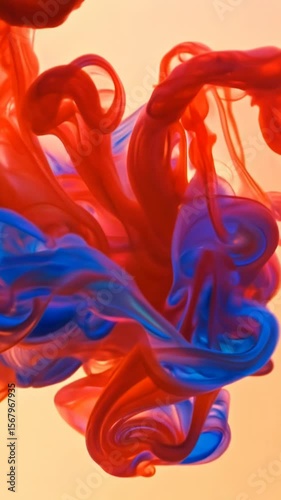 Colorful paint drops mix and swirl creating vibrant abstract patterns with red and blue pigments blending into dynamic fluid motion against neutral background producing artistic effects