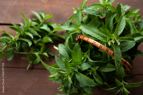 Bountiful harvest of fresh mint leaves gathered in a rustic basket on a wooden surface