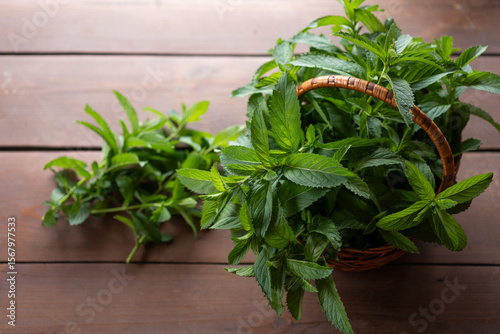 Freshly harvested mint in a rustic basket on a wooden table, symbolizing nature's bounty and culinary delight