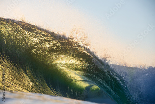 Photography A beautifully vibrant backlit emerald gold coloured glassy surfing wave breaking over a shallow reef