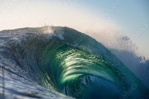 Canvas Print A beautifully vibrant backlit emerald coloured glassy surfing wave breaking over a shallow reef