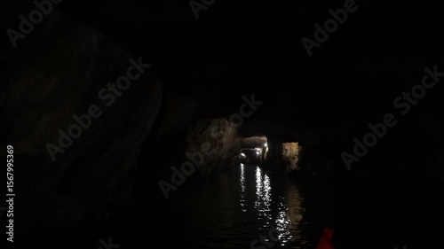Boat navigating underground river through Trang An Grotto, revealing geological wonders and hidden natural landscape in dark subterranean environment