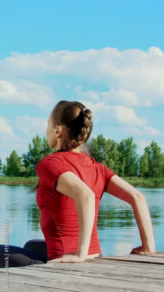 Beautiful, athletic young blond woman stretching, doing push-ups. Lake, river, blue sky and forest in the background, summer sunny day