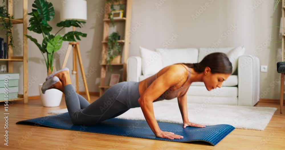 Young woman trains at home and does push-ups