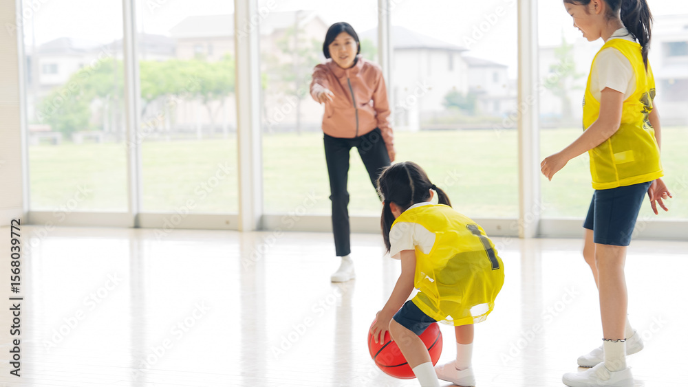 Obraz premium バスケットボールをする子供たちと指導する女性