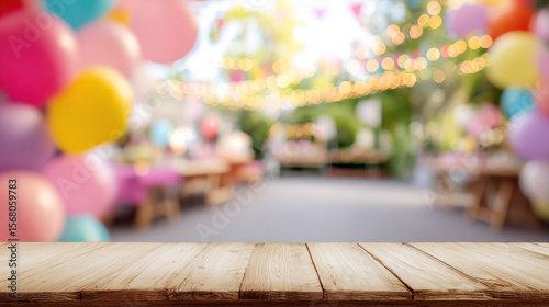Wooden table with blurred children’s birthday party background and colorful balloons