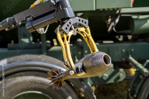 bomb disposal robot manipulator holding an unexploded mortar shell – specialized military equipment for EOD operations.