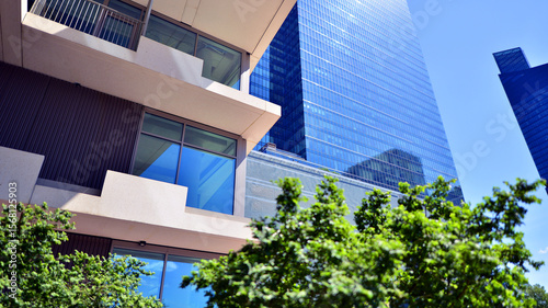 City life, urban landscape and ecology.  Modern office complex with glass facades and smooth lines against backdrop of green trees, concept of modern architecture. Organically building into nature.  