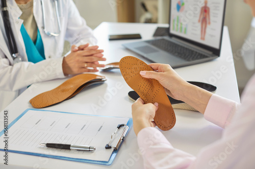 Canvastavla Patients hands holding leather orthopedic insole with pattern at orthopedists office for examination, custom insets for foot pain relief, comfortable walk