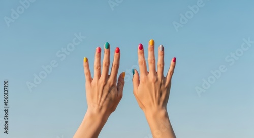 Colorful manicured female hands against clear blue sky