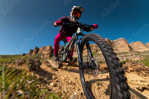 Wide angle shot from below of a cyclist in gear and protection quickly descending, feeling like he's running into the camera. Off-piste riding