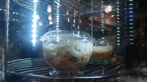 Sweet fruit and cream dessert on a glass spinning display case in a cafe. Cold dessert, ice cream.