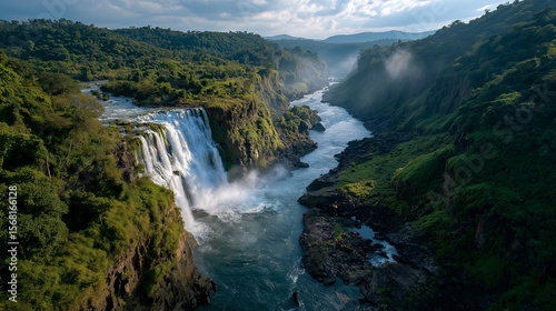 Majestic Waterfall Cascade: Witness the awe-inspiring power and beauty of a cascading waterfall as it plunges dramatically into a winding river, surrounded by lush, verdant forests and rolling hills.
