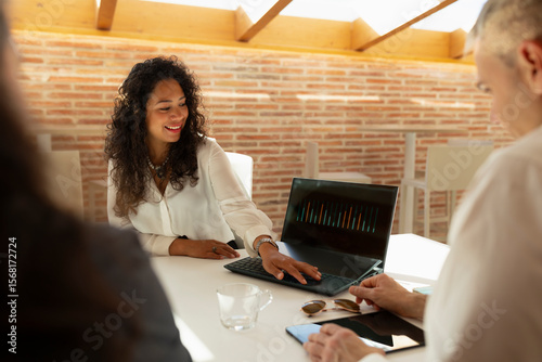 A young woman with Latin features, shows the data of a report, to her colleagues, during a meeting in the office